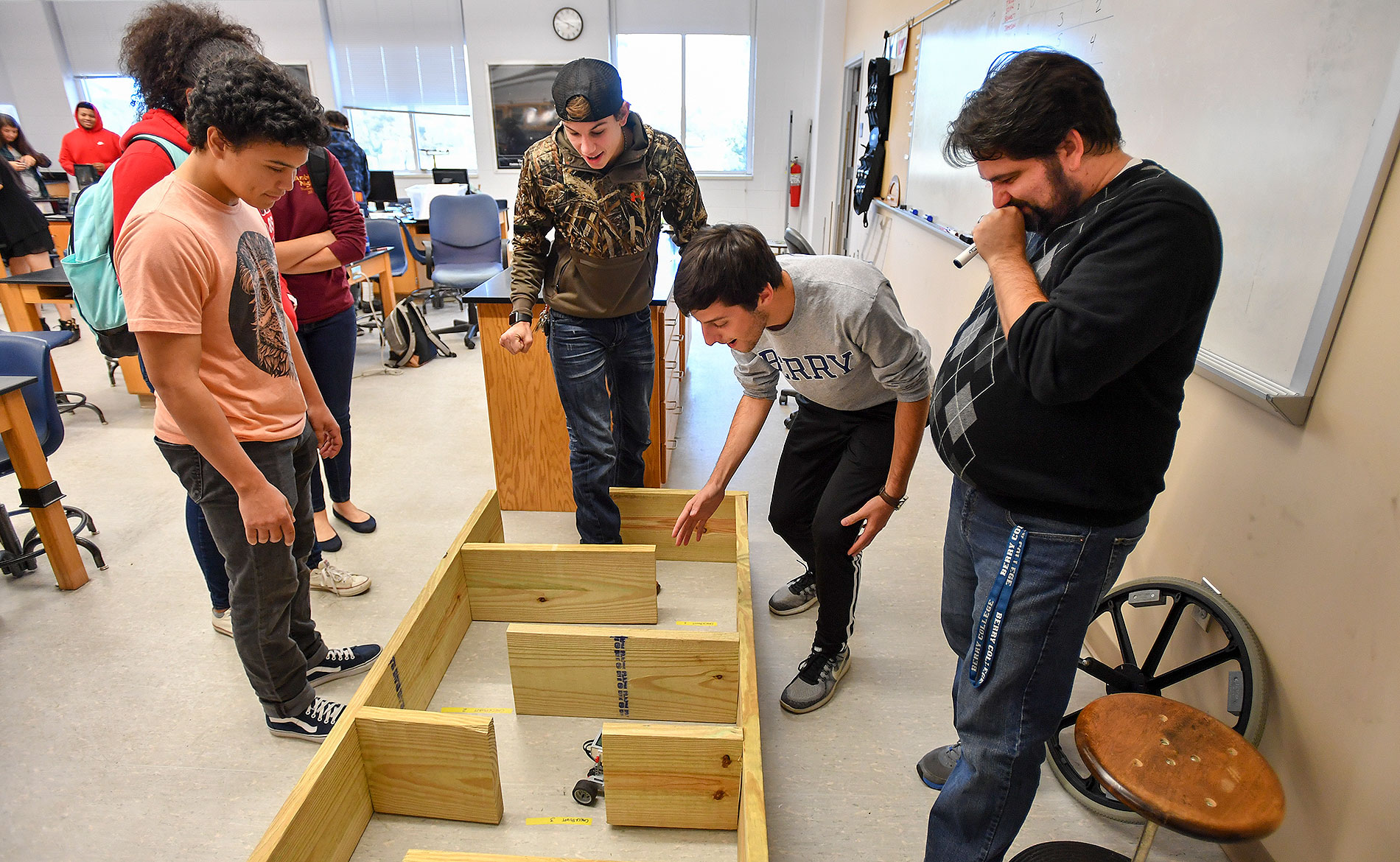 A group of students guiding a small robot through a maze