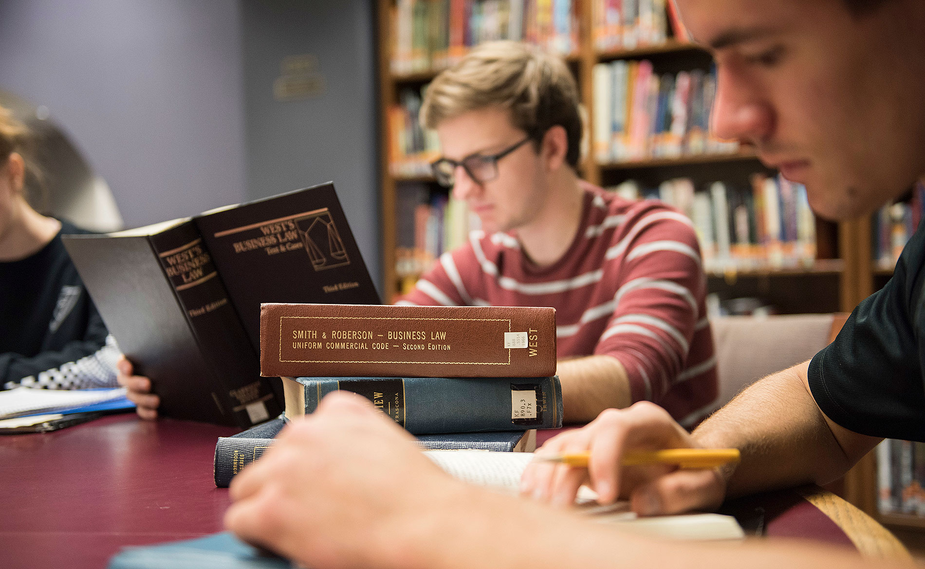 two students in the library reading business law text books