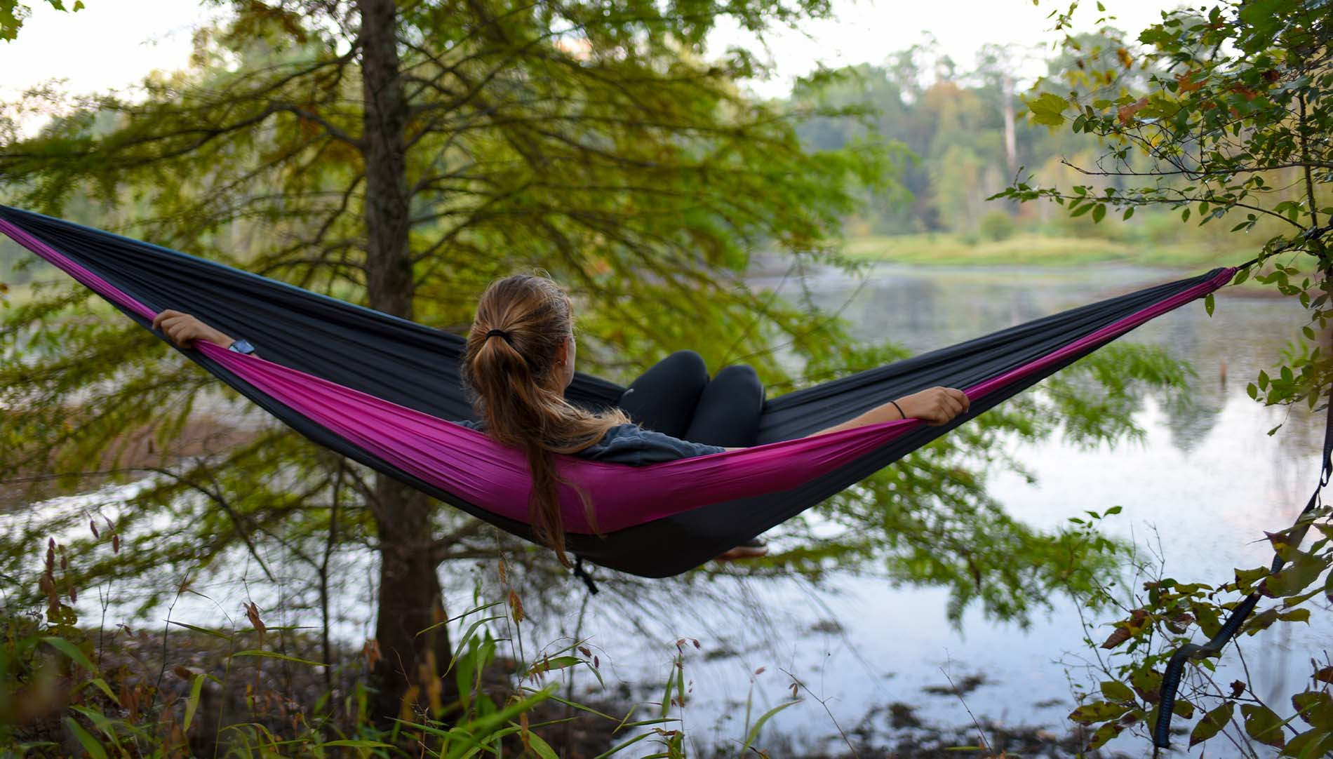 female student in a hammock by a lake