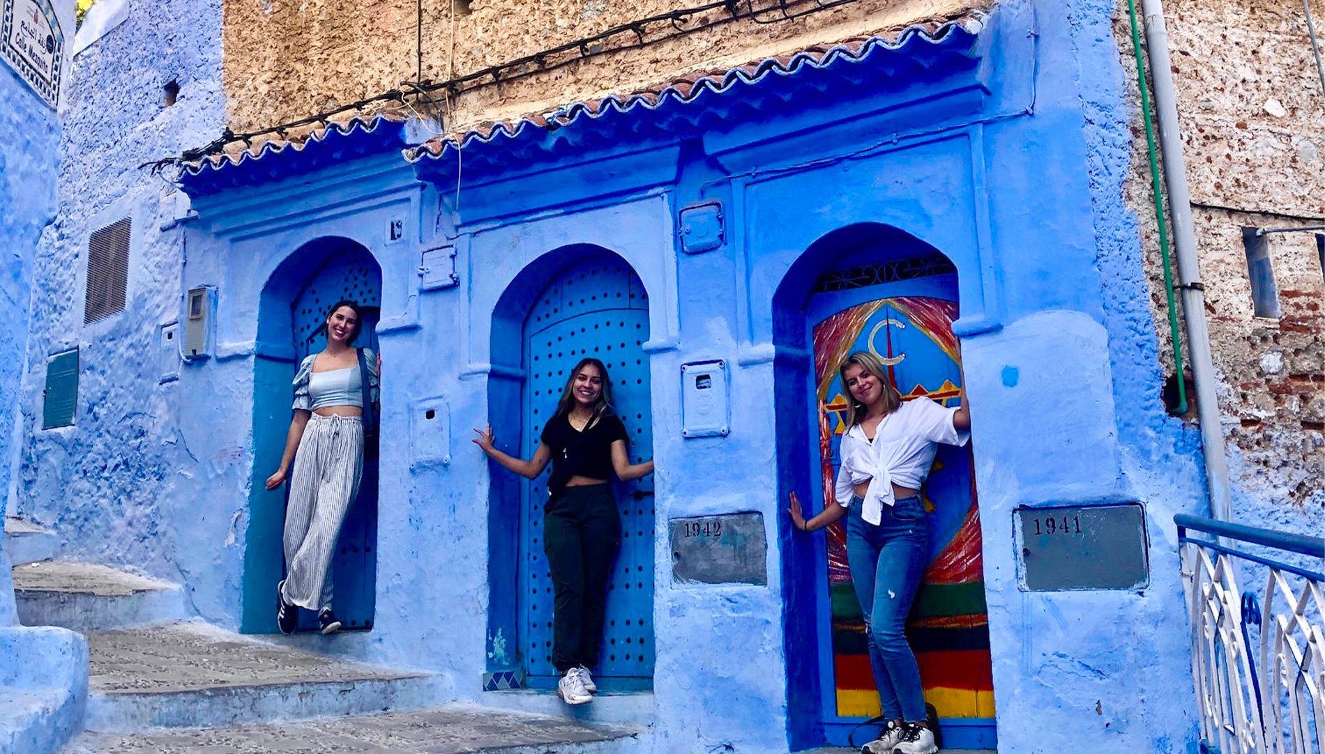 Three female students standing by blue architecture